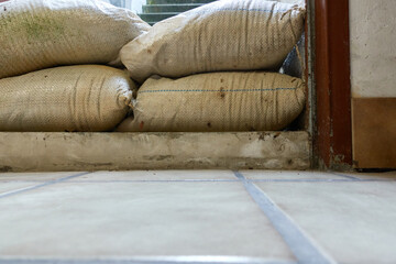 Fototapeta na wymiar Protective measure against floods in basements. Barrier made of sandbags lies in the entrance area of a residential building. Part of.