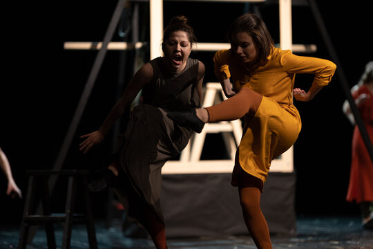 Actors and actresses perform a modern performance on the stage of the theater.