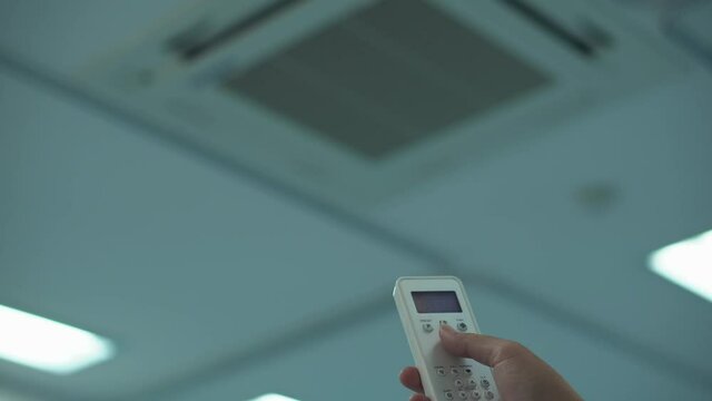 Hand with remote power on  air conditioning split.