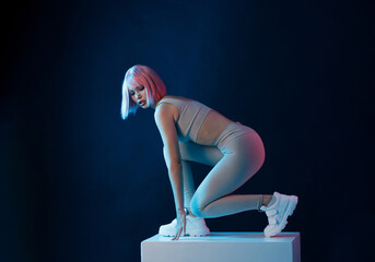 Woman in futuristic costume. Female in modern VR glasses interacting with network while having virtual reality experience. Augmented reality game, future technology, AI concept. VR. Neon blue light.