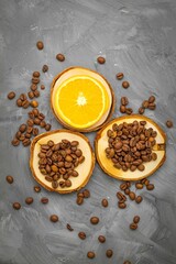 In the center on a gray background on three wooden stands are coffee beans and a juicy slice of orange