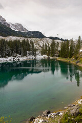 trees, mountain paths under the first snow on the lake of carezza in trentino alto adige in italy