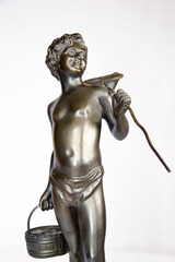 Details of a retro bronze statuette a boy with a crab net fishnet and basket isolated on white.