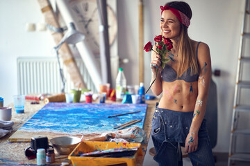 A thoughtful sexy and attractive female artist with roses is in a good mood in her studio while...