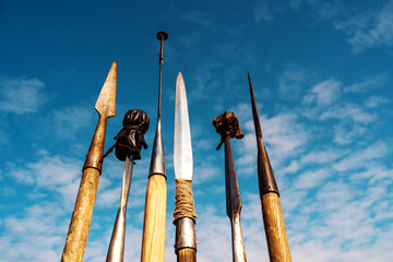 Medieval spears with metal tips and wooden handles against a blue sky. Exhibition of weapons of...