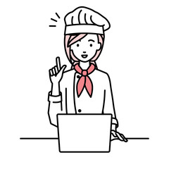 デスクで座ってPCを開いて何かひらめいた調理師の女性