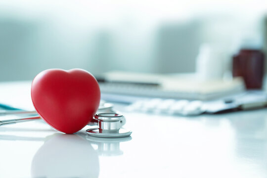 Red heart love shape hand exercise ball with doctor physician's stethoscope on white background: Hospital life insurance concept: World heart health day. doctor day, world hypertension day