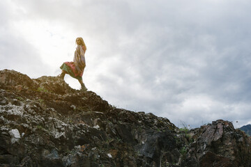 Woman silhouette in colorful ethnic dress walking in the mountains