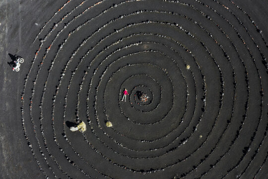 Woman motorcyclist lying on black ground ash volcanic slag. Spiral lined with stones in the zone of the Tolbachik volcano Kamchatka