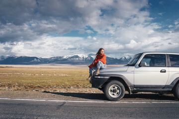 Fototapeta na wymiar Traveling female sitting on Off-road car in beautiful view of Altai mountain landscape and asphalt road