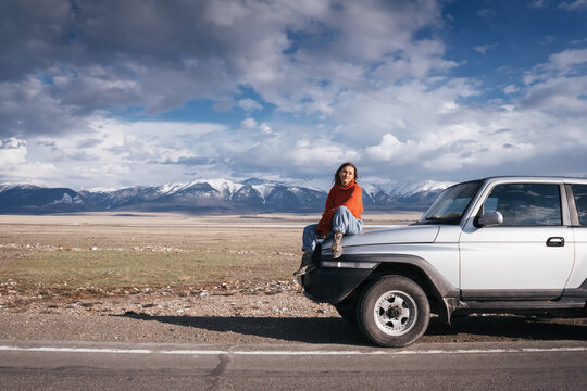 Traveling woman sitting on Off-road car in beautiful view of Altai mountain landscape and  asphalt road
