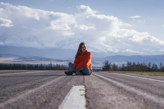 Happy traveling woman on perfect asphalt road in mountains