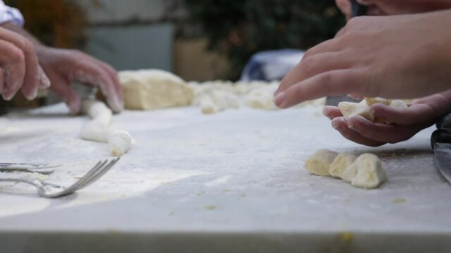 Mani che preparano gli gnocchi, tipico primo piatto della tradizione italiana
Preparazione degli gnocchi di patate, piatto tipico della cucina italiana