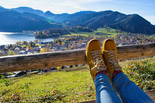 Womans feet with a beautiful mountain landscape as a background. Womans feet in yellow touristic shoes with a landscape of Schliersee lake in the german Alps during Fall as a background, Bavaria, Germ