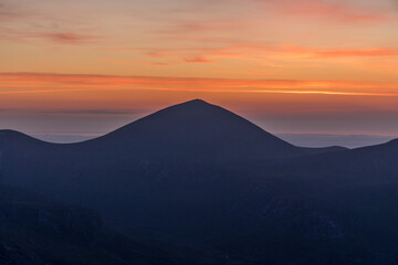 Watching the Sunrise on Slieve Binnian during summer, looking towards Slieve Donard, Mourne mountains, County Down. Northern Ireland