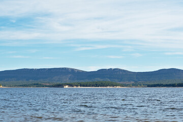 Waters of the Cuerda del Pozo reservoir. In the background pine forests and rocky mountains. Cloudy day. Soria, Spain.