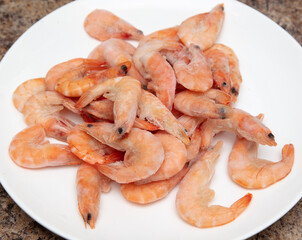 Red frozen shrimps on a white plate.