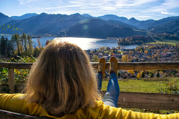 Woman watching at a beautiful mountain landscape. 
A middle aged Woman contemplates a landscape of Schliersee lake in the german Alps during Autumn, Bavaria, Germany