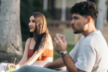 Young woman sitting next to a man drinking soda during sunset
