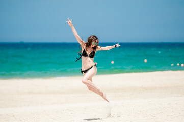 Fototapeta na wymiar Girl Jumping when running on the beach ( Summer Vibes ) welocme to troipcs