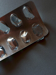Empty pill blister package on grey background. Concepts of drug shortage and death. Vertical photo