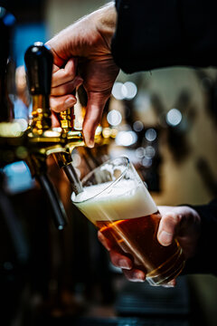 bartender hand at beer tap pouring a draught beer in glass serving in a bar or pub