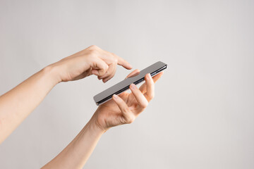 Slim modern smartphone in a woman's hand, use the Internet or apps on your phone, light grey background, layout for your design.