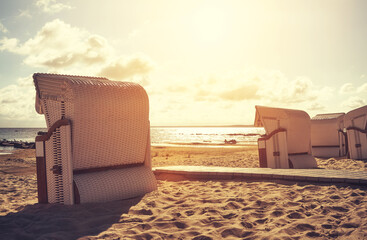 Wicker beach chairs on a beach at sunset, color toning applied, selective focus.