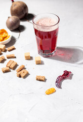 A glass of beet kvass on a light background, with rye breadcrumbs, raisins and beet tubers
