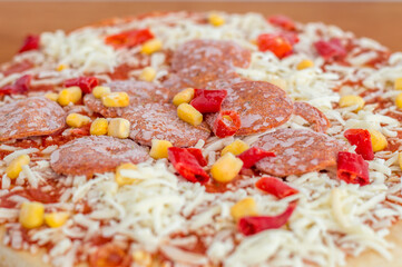 Detail of frozen pizza with pepperoni, peppers, corn.