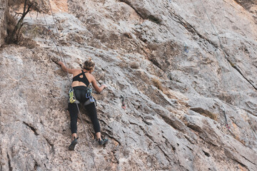 a girl climbing a rock in the open air.