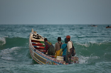 Nouakchott. Mauritania. Struggling with the waves of the surf, fishermen daily sail out on special wooden boats with a motor for several days in the open Atlantic Ocean for fishing.