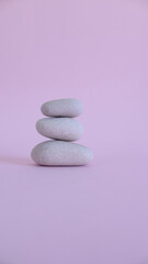 Fototapeta na wymiar Mound of white zen stones on pink background