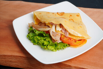Tortillas stuffed with tuna and bacon and tomatoes on a wooden chopping board close up