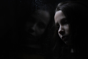portrait of a girl with a reflection on a dark background by the window