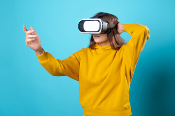 VR gamer, a young woman in a youth outfit uses a virtual reality helmet. Brunette in a yellow...
