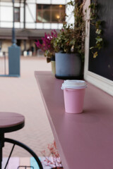 Pink disposable recyclable cup on wood rack outdoors takeaway concept, cup template.