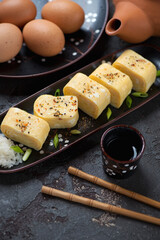 Sliced tamagoyaki or sweetened japanese egg roll, vertical shot on a brown stone surface, middle close-up