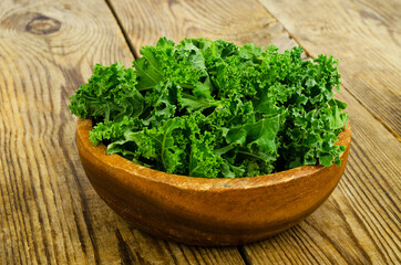 Fresh green sabellica leaves on wooden background, healthy organic food.