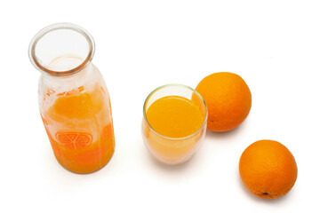 Top view of a ripe oranges, glass bottle and mug with fresh squeezed orange juice on white background.