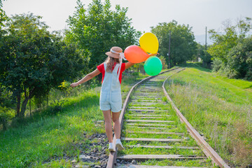 one tourist walks with colored balloons on the railway