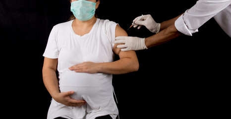 pregnant woman getting covid-19 vaccine on black background