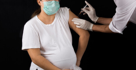 pregnant woman getting covid-19 vaccine on black background