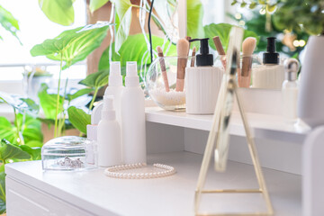 Table mirror on dressing table with make up accessories. Self-Care. White, pastel interior