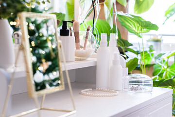 Reflection of christmas tree, light bulbs, in table mirror on woman dressing table with make up accessories