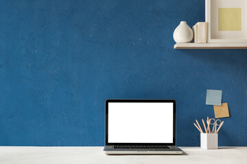 Home office desk with screen mockup and blue wall copy space. Banner.	

