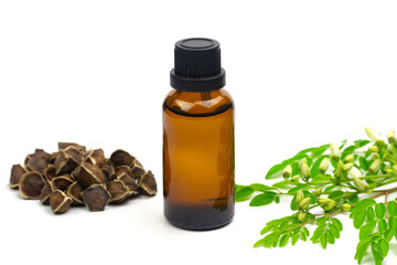 Oil of Moringa in bottle with green leaves and seeds isolated on white background. Moringa oleifera tropical herb product concept. 