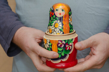 An adult male holding a wooden matryoshka doll. An uncovered tra