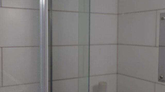 a woman's hand opens the glass door to the shower stall, transparent wall, close-up