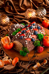 Christmas fruit chocolate cake with berries and fruits with edible Christmas decoration. Close up.